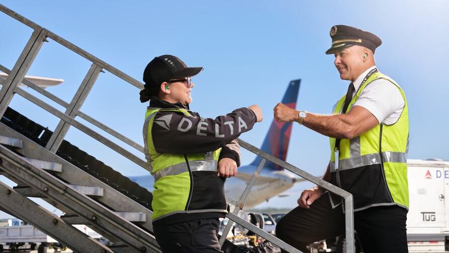 Delta pilot and ground agent giving fist bump on the ramp